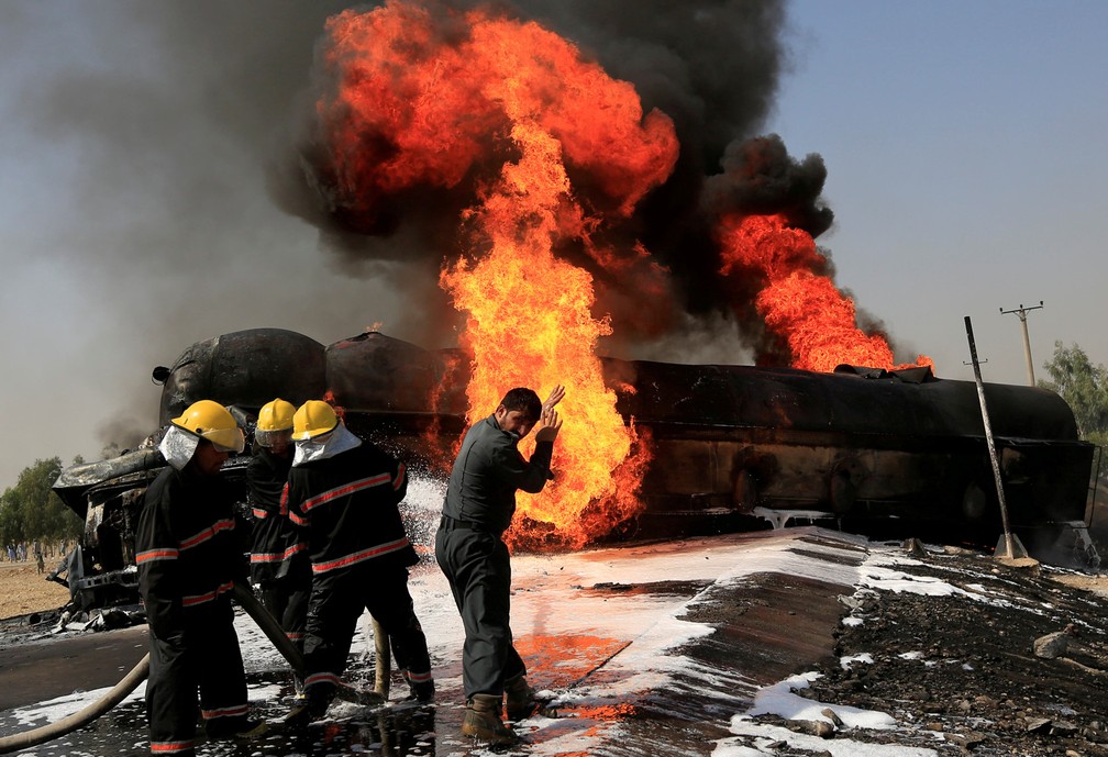 Bombeiros trabalham para controlar um incêndio num tanque de combustível que foi atingido por uma bomba magnética nos arredores de Jalalaad, no Afeganistão (Foto: Parwiz/Reuters)