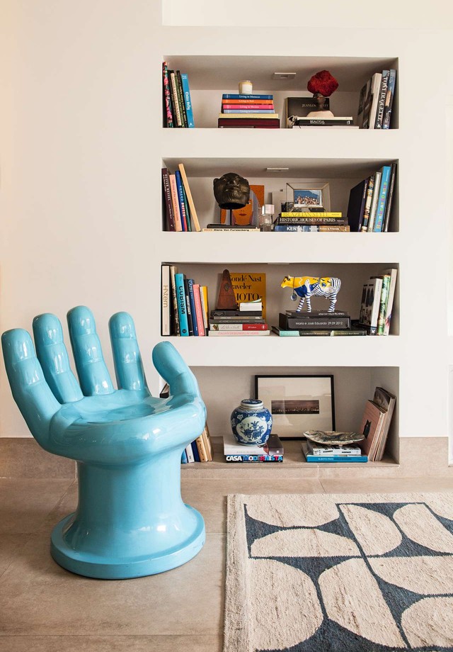 O toque de azul na sala de TV está na divertida cadeira em forma de mão e no tapete com estampa by Rem Koolhaas (Foto: Divulgação)