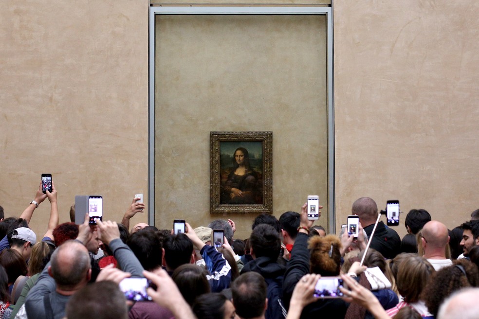 Visitantes do Museu do Louvre, em Paris, tiram foto da 'Mona Lisa' (1503-1506), de Leonardo da Vinci, em imagem de 9 de abril de 2018 — Foto: Pedro Fiuza/NurPhoto via AFP/Arquivo