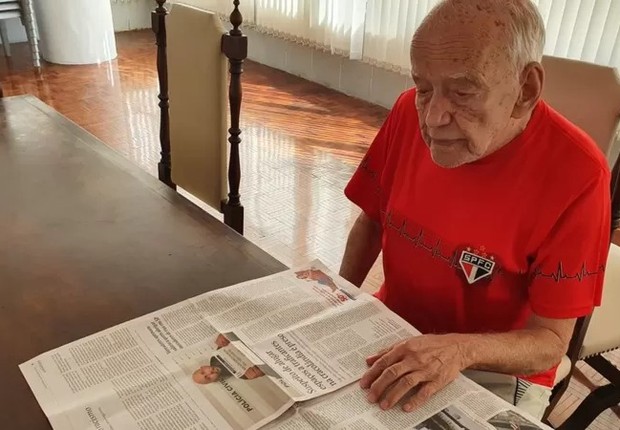 O comerciante aposentado Álvaro Pereira vê no jornal onde vão passar os jogos do São Paulo. Se é em algum serviço de streaming, precisa pedir ajuda ao filho (Foto: THAIS CARRANÇA/BBC BRASIL)