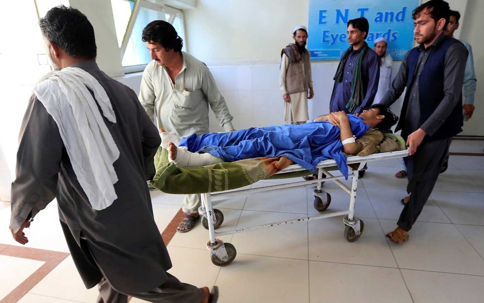 Ferido Ã© transportado em uma maca para hospital, apÃ³s explosÃµes durante jogo de crÃ­quete no AfeganistÃ£o (Foto: Parwiz / Reuters)