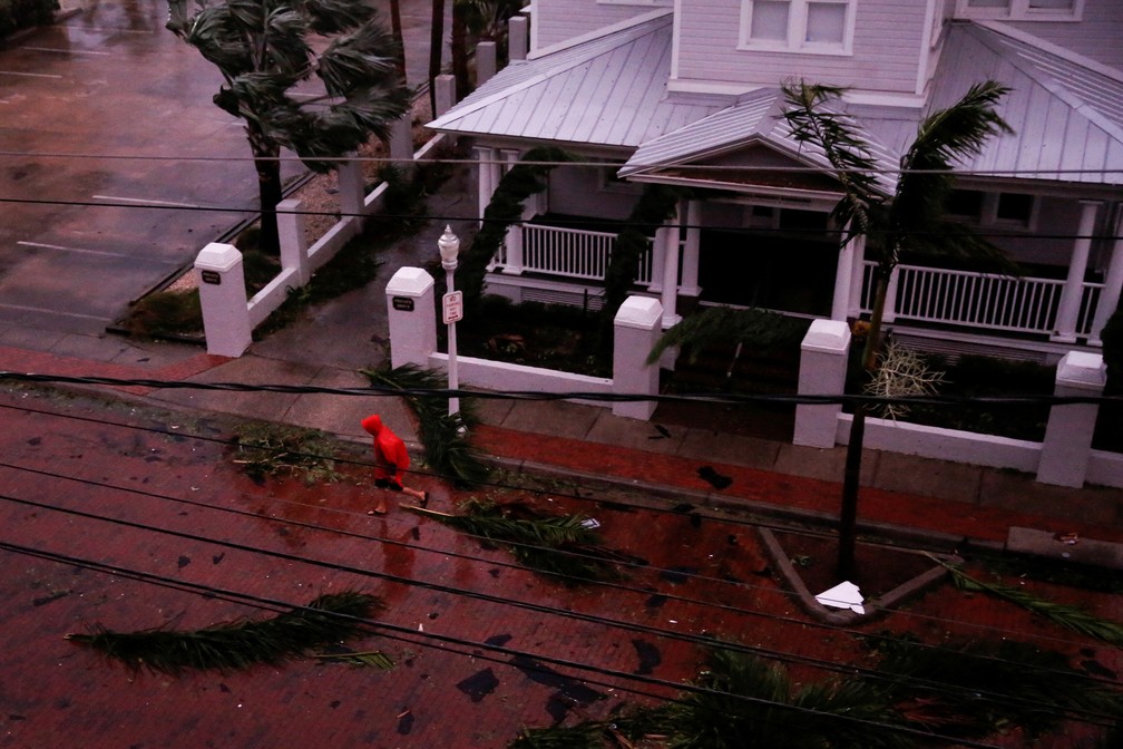 Um homem caminha entre folhas de palmeiras caídas e escombros em uma rua no centro da cidade enquanto o furacão Ian atinge o sudoeste da Flórida, em Fort Myers, EUA  — Foto: REUTERS/Marco Bello