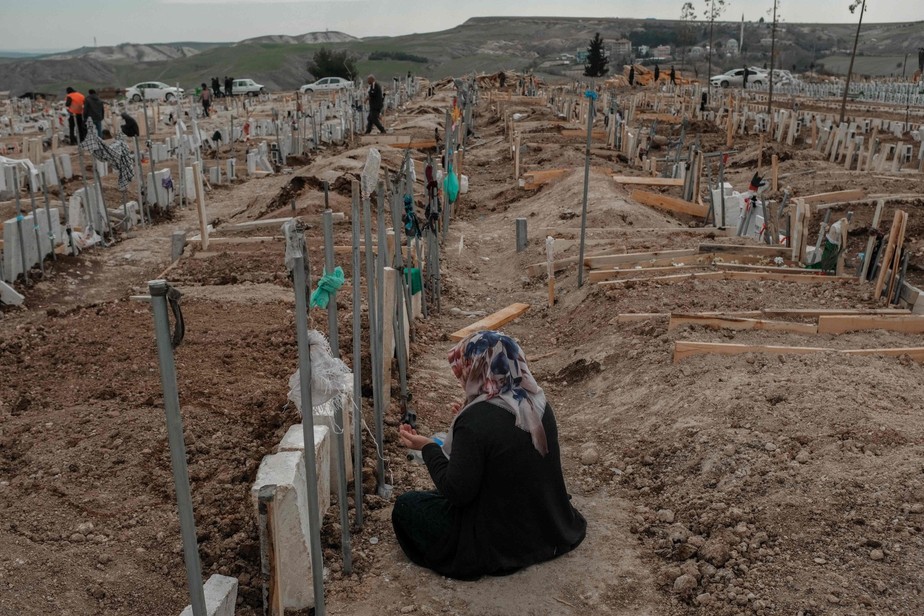 Uma mulher em frente a uma sepultura de vítimas do terremoto na Ucrânia