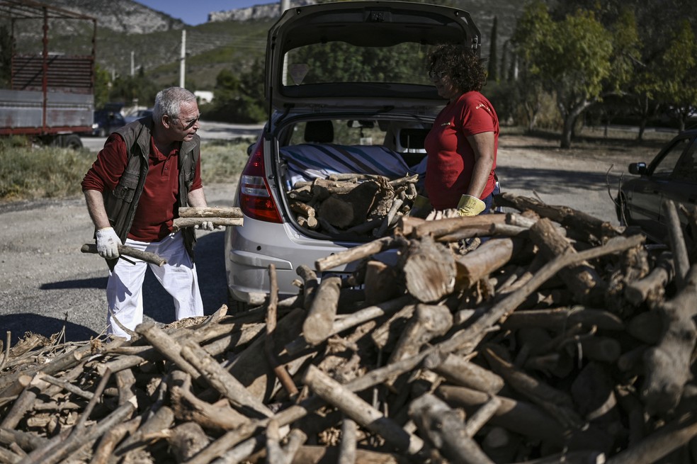 Populares gregos pegam lenha distribuída gratuitamente pela prefeitura — Foto: ARIS MESSINIS / AFP