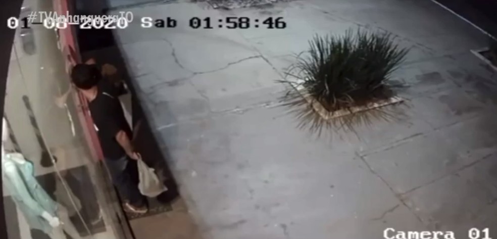 Momento em que criminoso forçou a porta de loja no centro de Palmas — Foto: Reprodução/TV Anhanguera