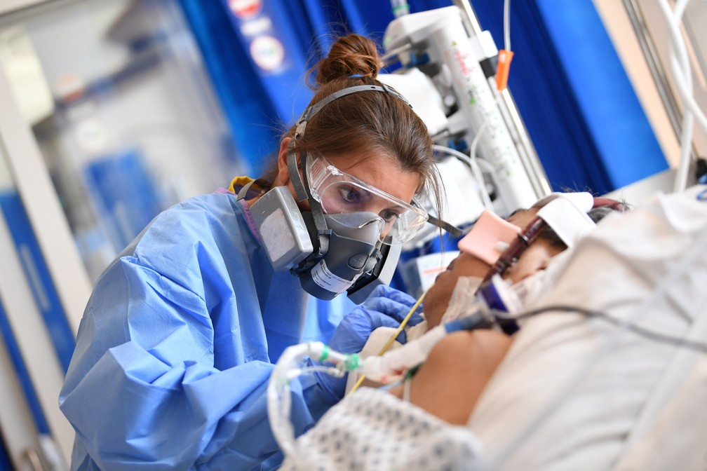 Profissional de saúde usa máscara elastomérica para cuidar de paciente com Covid-19 no Hospital Royal Papworth, em Cambridge, na Inglaterra, em maio de 2020. — Foto: Neil Hall/Pool via Reuters