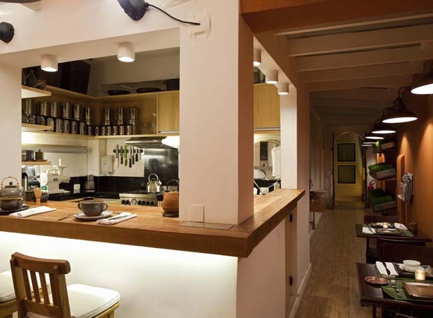 No andar superior, o restaurante My Green Bar serve refeições saudáveis e oferece aulas de culinária. O espaço reproduz o ambiente de uma cozinha integrada, com paredes laterais na cor terracota (Foto: Divulgação)