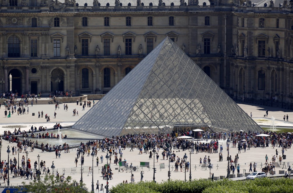 Na foto, de julho de 2019, pessoas são vistas na praça com a pirâmide em frente ao Museu do Louvre, em Paris. — Foto: Regis Duvignau/Reuters