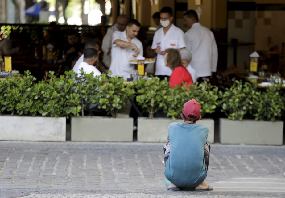 Morador de rua aguarda pelos 'restos de comida' dos clientes de um restaurante