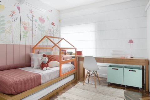 Neste quarto projetado por Paula Müller, rosa e azul contrastam com a marcenaria de madeira. Um painel florido ganhou mais vida com a estrutura de casinha na cama