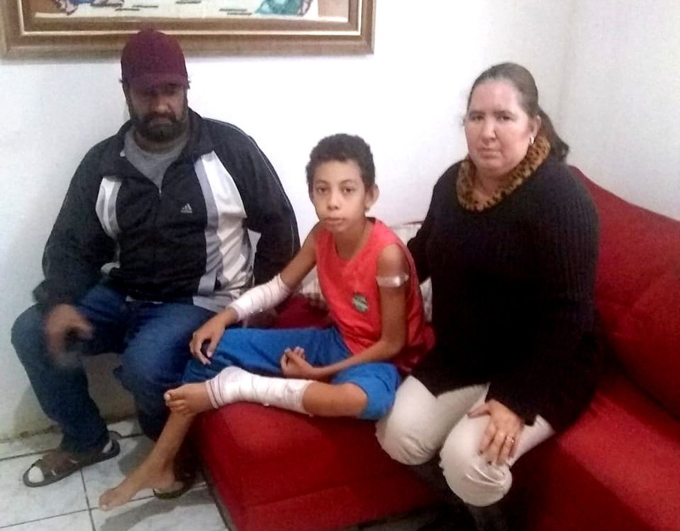 Vinícius com o pai e a madrasta, durante sua recuperação em casa: 60 pontos para fechar ferimentos na perna e no braço — Foto: Arquivo pessoal