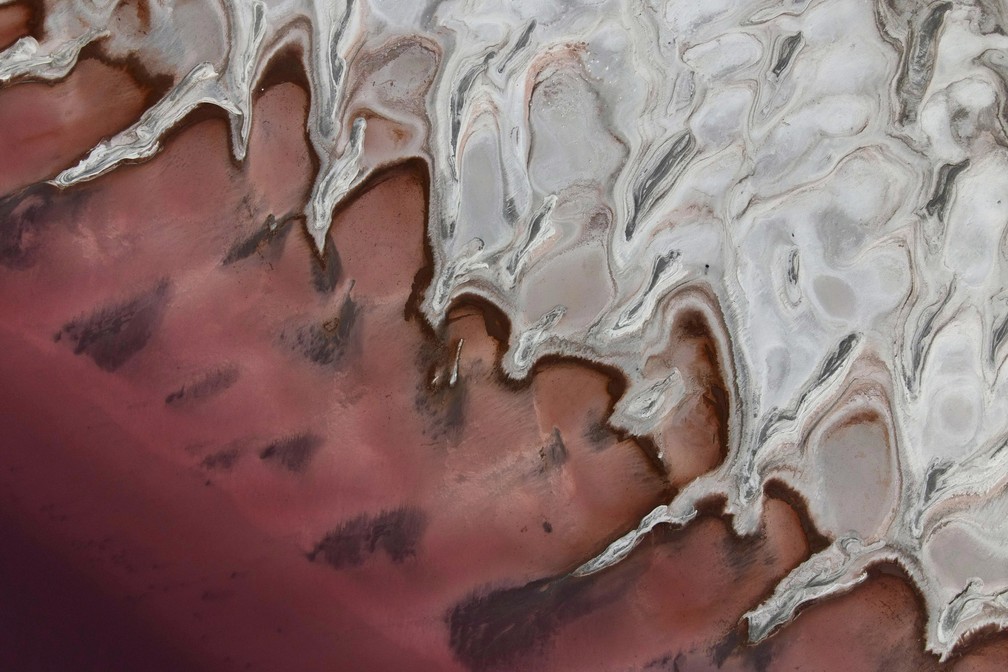 8 de outubro - Padrão com tons de vermelho e branco é visto do alto às margens do Grande Lago Salgado em Howell, Utah, nos EUA. O fenômeno é resultado da ação de uma bactéria, que se multiplica quando a salinidade das águas aumenta — Foto: Julio Cortez/AP