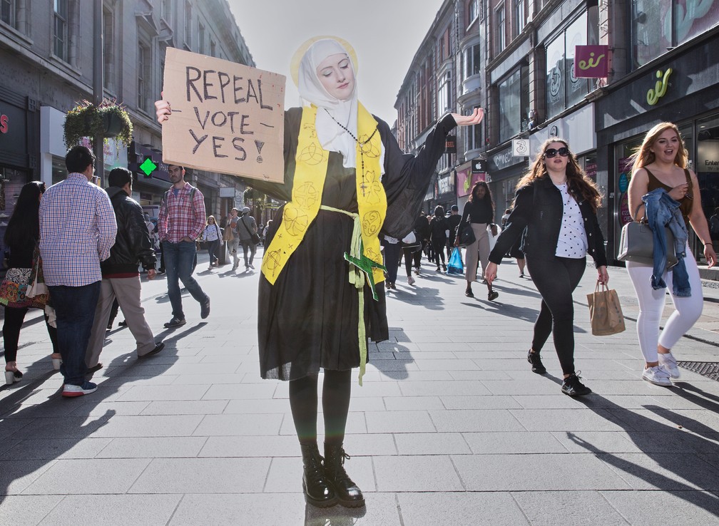 Mulher segura cartaz pedindo voto a favor de regras menos rígidas contra o aborto na Irlanda — Foto: Olivia Harris/Reprodução