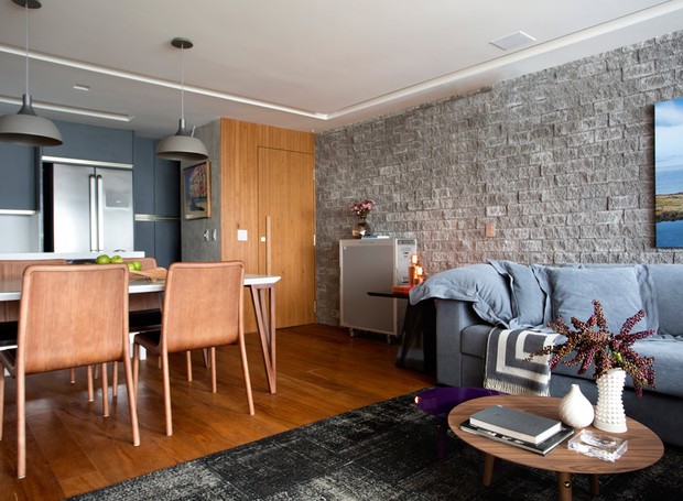 Com ambientes integrados, o living de 37 m², ganhou piso de peroba mica - à venda na Madeireira da Hora. A parede de apoio ao sofá foi revestida com Hardscape, da Ekko Revestimentos (Foto: Denílson Machado - MCA Estúdio/Divulgação )