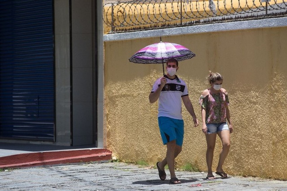 Imagem de um homem e uma mulher caminhando pela calçada com máscaras, em Fortaleza, para proteção contra coronavírus. — Foto: Fabiane de Paula/ SVM