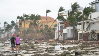 Pessoas caminham ao longo da praia olhando para a propriedade danificada pelo furacão Ian em Bonita Springs — Foto: Sean Rayford / Getty Images via AFP