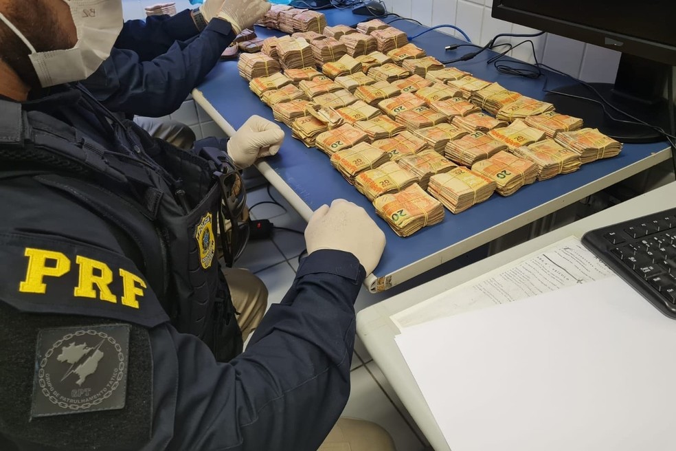 Policial rodoviária federal contou dinheiro apreendido com homem flagrado com R$ 115 mil em maços de cédulas — Foto: PRF/Divulgação