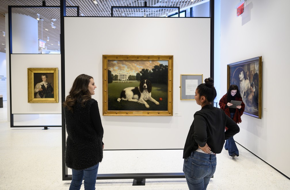 Mulheres observam quadro de cachorro no Museu Americano do Cachorro — Foto: Johannes EISELE / AFP