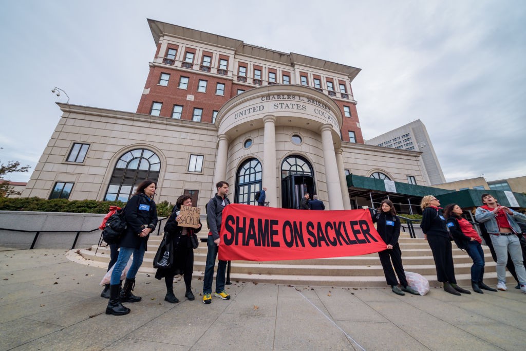 Protestantes levantam cartazes contra a Purdue Pharma em dia de audiência (Foto: Getty Images)