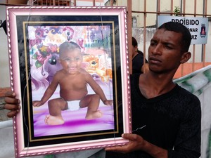 Morador exibe foto da criança que foi morta após ação da polícia (Foto: Ruan Melo/G1)