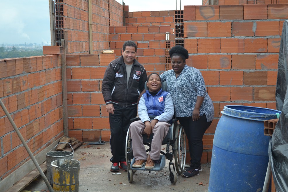 Andrey com a mÃ£e Matilde e o pai Ailton na construÃ§Ã£o da casa acessÃ­vel no Jardim Layr, em Mogi das Cruzes.  â Foto: Natan Lira/G1