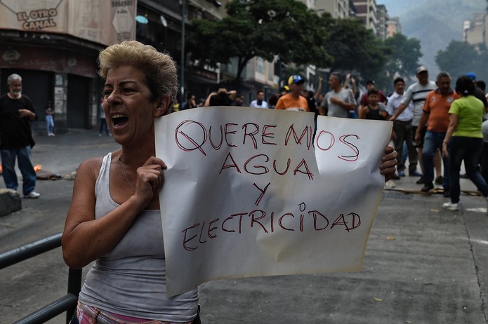 'Queremos água e eletricidade', diz cartaz de venezuelana que protesta em Caracas contra apagão na Venezuela — Foto: Federico Parra/AFP