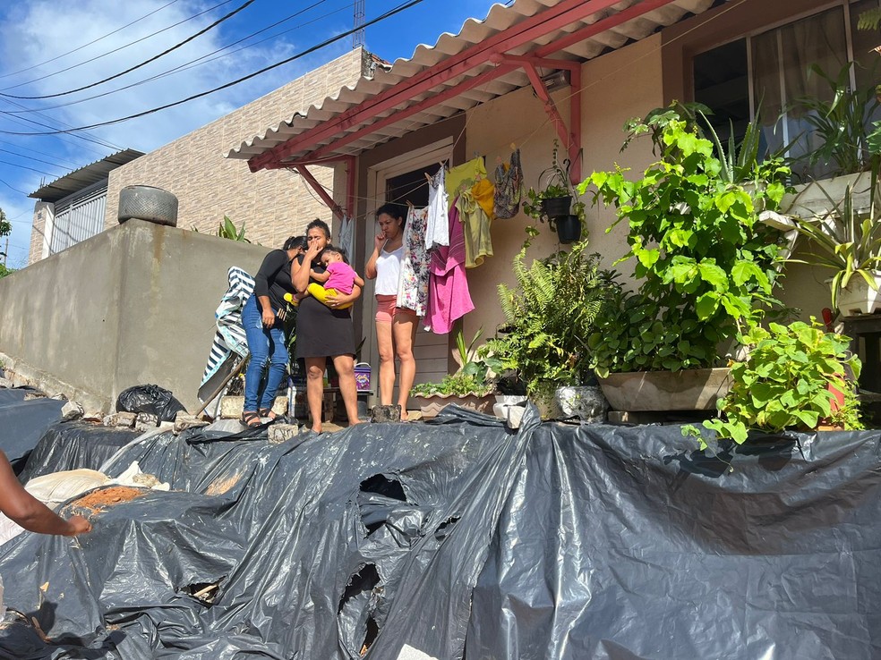 Moradores 'ilhados' na frente de casa, na Toca da Raposa, em Nova Parnamirim — Foto: Vinícius Marinho/Inter TV Cabugi