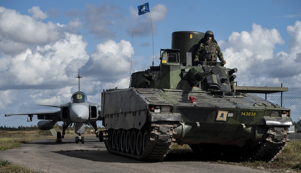 Avião militar e tanques da Suécia na ilha de Gotland, destino turístico do país onde o governo anunciou aumento da presença do Exército por conta de ameaças da Rússia no mar Báltico — Foto: Associated Press