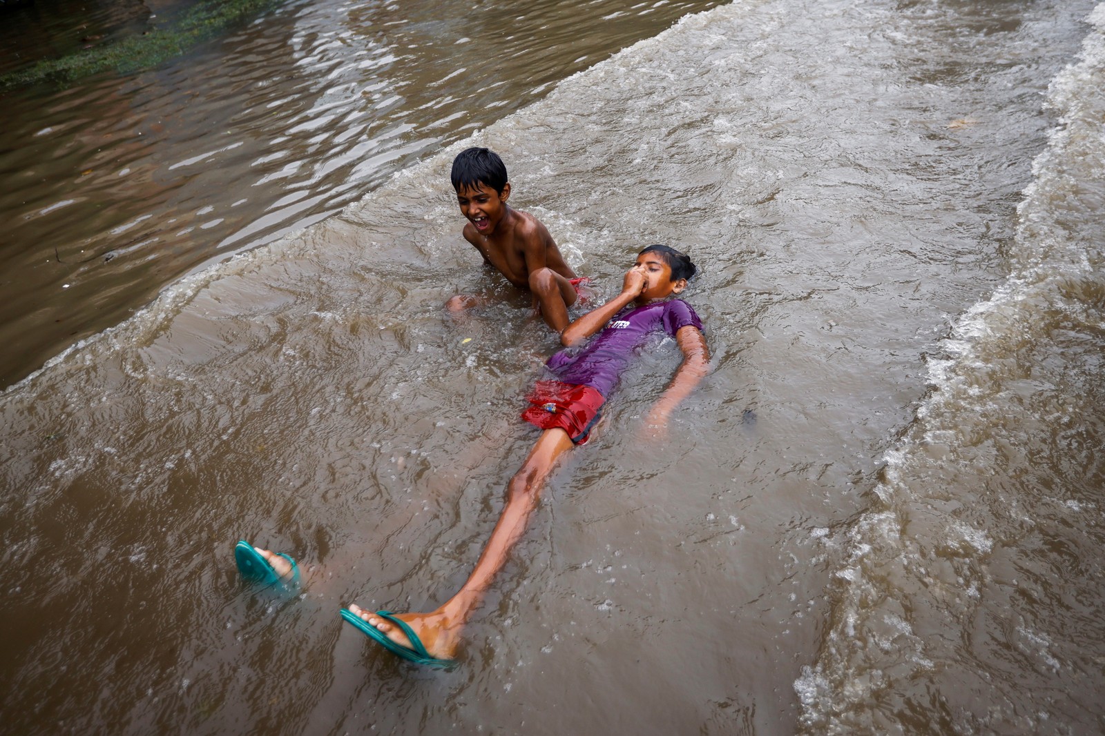 Crianças brincam em uma rua inundada após fortes chuvas em Nova Delhi, ÍndiaREUTERS