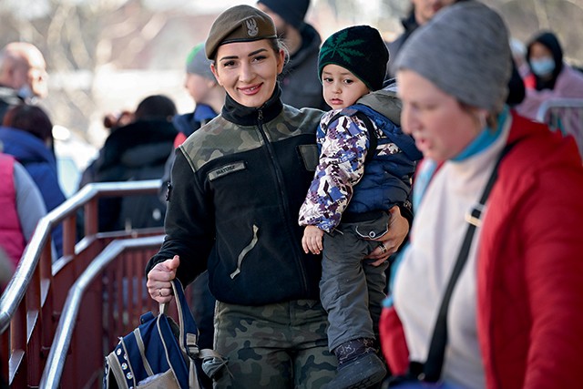 Soldada ucraniana carrega criança em Przemyl, cidade da Polônia que recebeu refugiados  da guerra (Foto: Getty Images)
