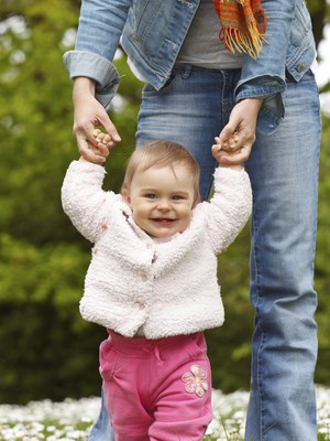 Bebê andando com ajuda da mãe (Foto: Shutterstock)