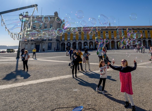 LISBON, PORTUGAL - FEBRUARY 14: Children try to catch soap bubbles produced by a street artist in Praça do Comercio, a favorite spot for tourists, on February 14, 2019 in Lisbon, Portugal. The country received 12,762,532 foreign tourists in 2018, reaching (Foto: Corbis via Getty Images)