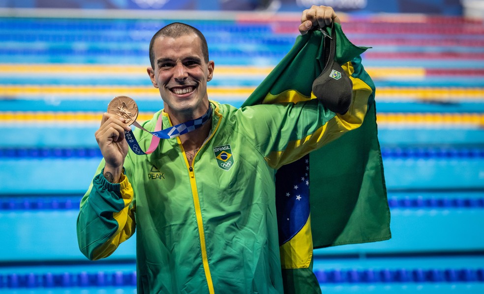 Bruno Fratus com a medalha de bronze dos 50m livre da nata��o nas Olimp�adas de T�quio e a bandeira do Brasil � Foto: Jonne Roriz / COB