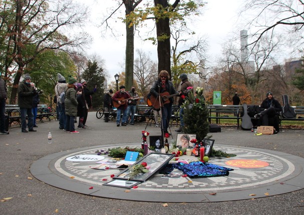 08 December 2020, US, New York: Photos, flowers and candles are on display at the Strawberry Fields Memorial in Central Park in memory of musician John Lennon. Exactly 40 years ago the Beatles musician was shot in New York. The murderer is still in prison (Foto: dpa/picture alliance via Getty I)
