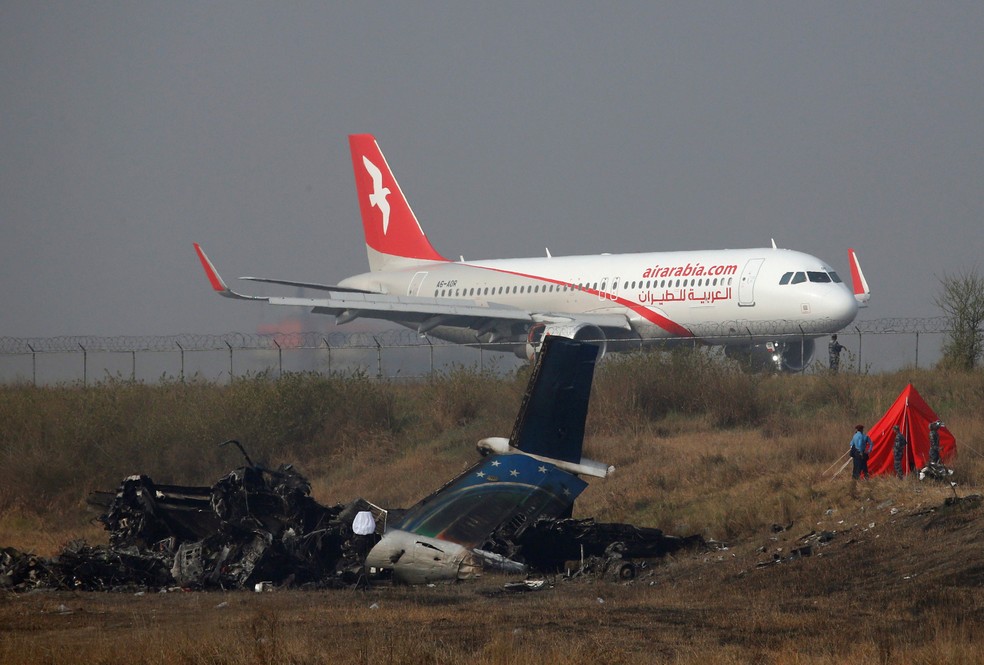 Avião pousa nesta terça-feira (13) perto de local onde aeronave caiu ao tentar aterrissar no aeroporto de Katmandu, no Nepal  (Foto: Navesh Chitrakar/ Reuters)