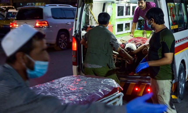 Equipe médica leva um homem ferido em uma ambulância para um hospital após duas fortes explosões fora do aeroporto de Cabul
