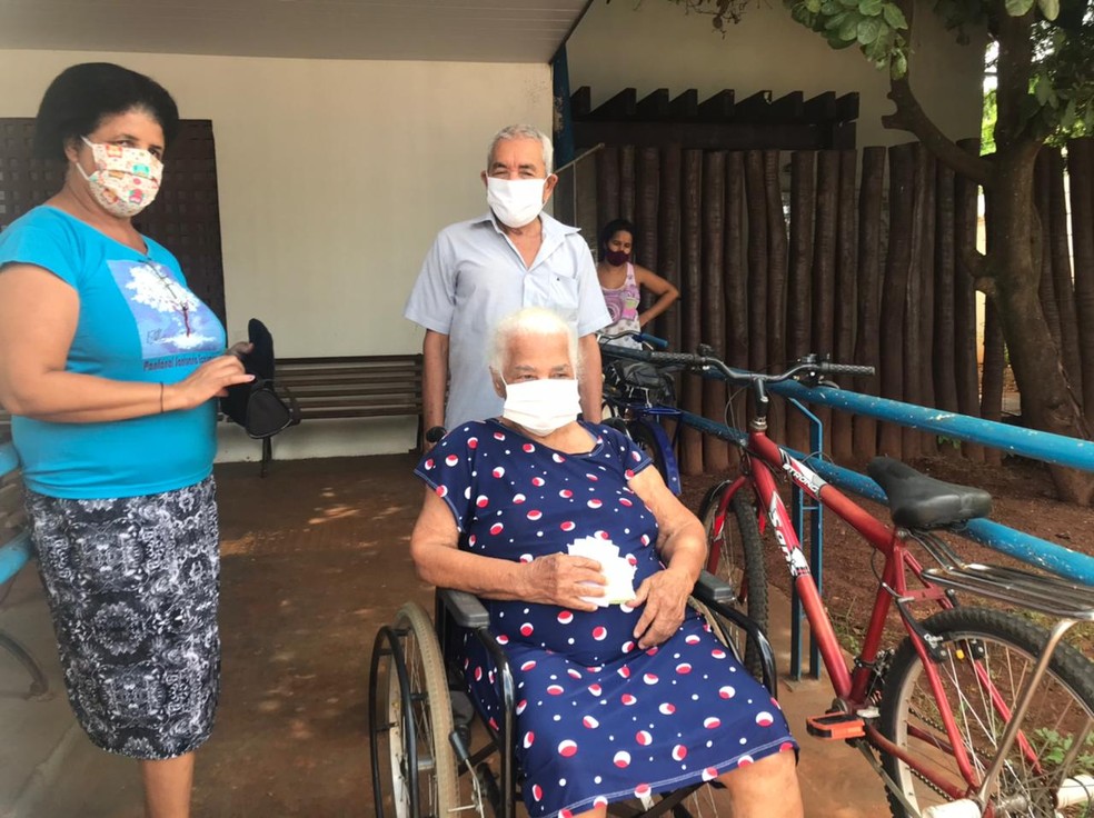 Amáveis Martins, de 100 anos (na cadeira de rodas) foi a primeira a ser vacinada em uma Clínica da Família de Campo Grande (MS) — Foto: Graciela Andrade/TV Morena