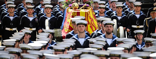 Membros da Marinha Real caminham à frente e atrás do caixão da Rainha Elizabeth II durante último adeus à monarca — Foto: Marco BERTORELLO / POOL / AFP