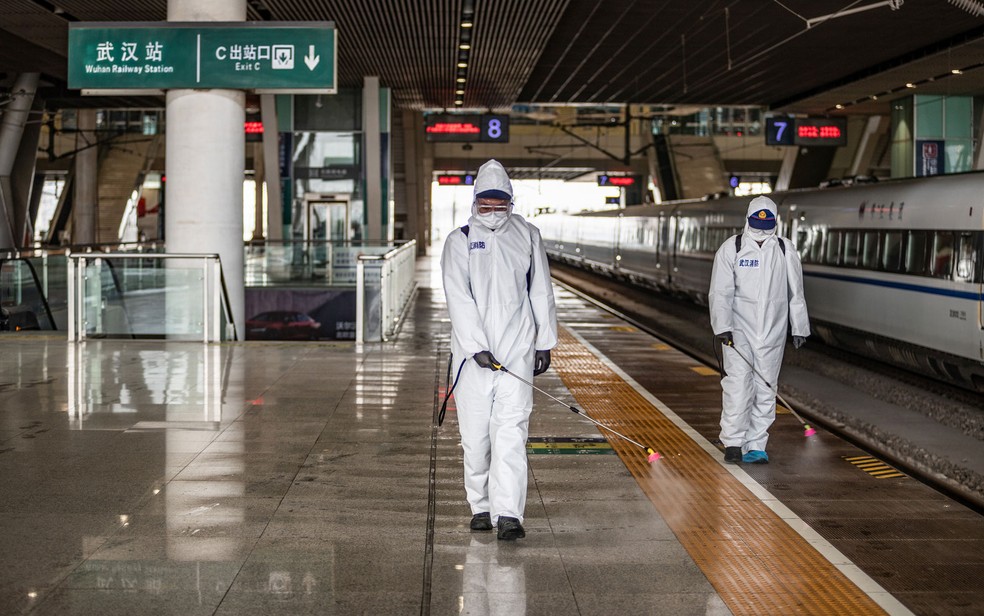 Funcionários espalham desinfetante na Estação de Trens de Wuhan, na província de Hubei, na China, preparando o local para a reabertura após fim da quarentena, na terça-feira (24) — Foto: STR/AFP