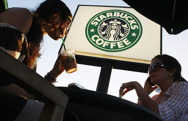 Clientes sentados em mesas diante de loja do Starbucks (Foto: Getty Images)