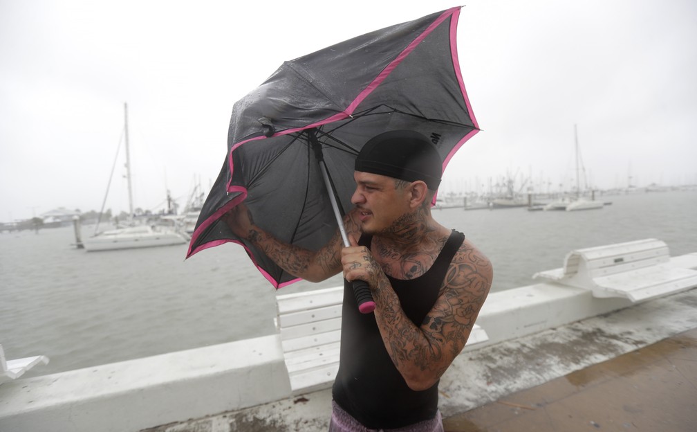 Chris Headen se protege de vento forte com a chegada do furacão Hanna neste sábado (25), em Corpus Christi, no Texas — Foto: Eric Gay/AP