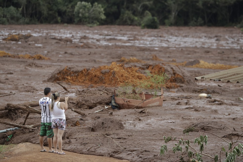 Casal com familiares desaparecidos observa a área inundada após o rompimento da barragem da Vale em Brumadinho. — Foto: André Penner/AP