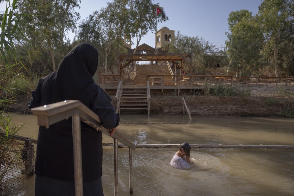 Olga Bokkas, uma visitante de Connecticut, EUA, entra nas águas do Rio Jordão no local de batismo Qasr al-Yahud, próximo à cidade de Jericó, na Cisjordânia — Foto: Oded Balilty/AP