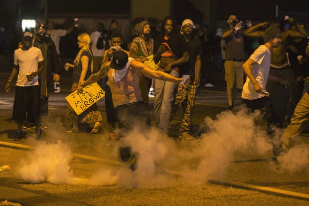 Manifestante chuta lata de gás lacrimogêneo atirada pela polícia durante protestos em Ferguson, no Missouri, neste domingo (17) (Foto: Lucas Jackson/Reuters)