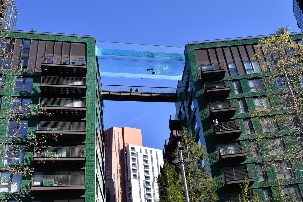 Modelo nada em uma piscina de acrílico transparente fixada entre dois blocos de apartamentos em Embassy Gardens, em Londres. — Foto: Justin Tallis/AFP