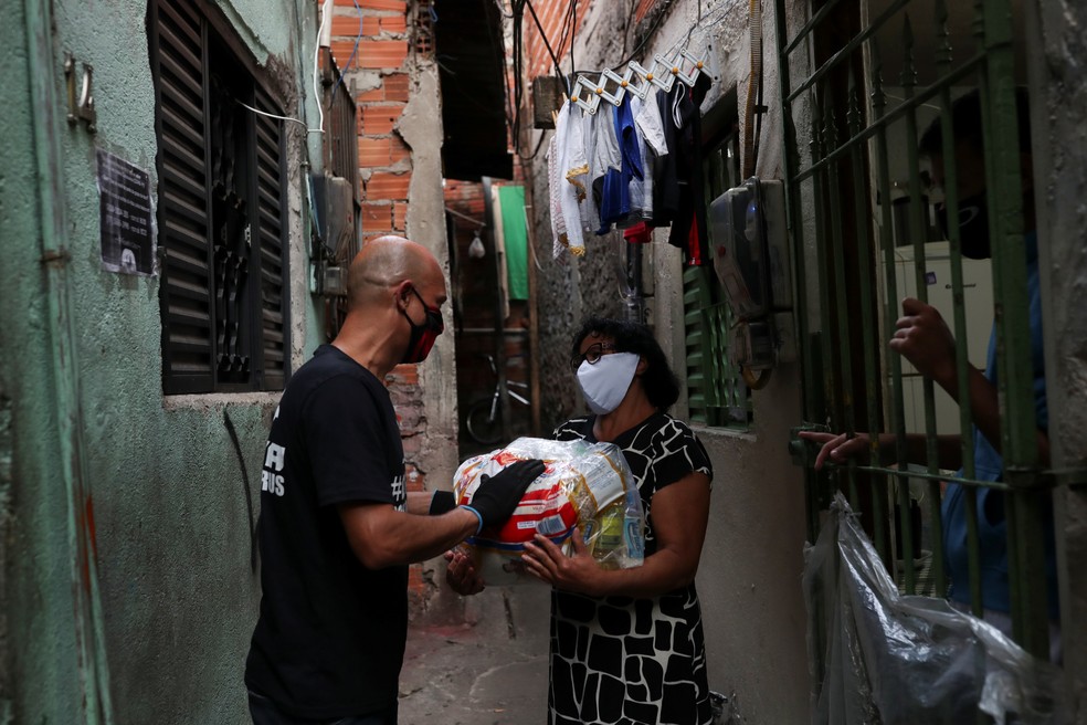 Mulher recebe alimentos distribuídos pela organização não governamental Central Única das Favelas (CUFA), que disponibiliza ajuda para famílias pobres em meio ao surto de doença por coronavírus (Covid-19) na favela de Heliópolis, em São Paulo — Foto: Amanda Perobelli/Reuters