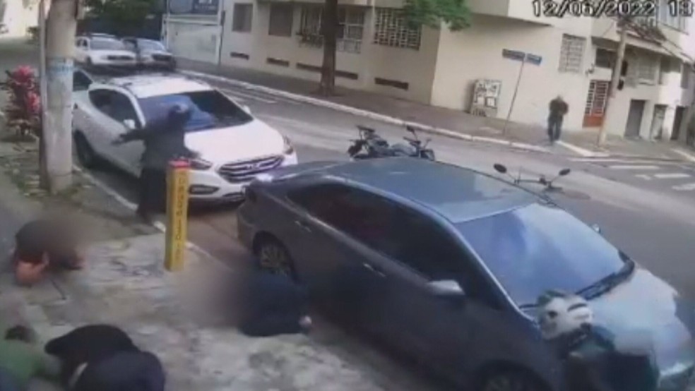 Homem (à esquerda, em frente ao carro branco) foge após ser ferido na perna em arrastão nos Jardins, mas foi preso ao procurar atendimento médico em hospital — Foto: TV Globo
