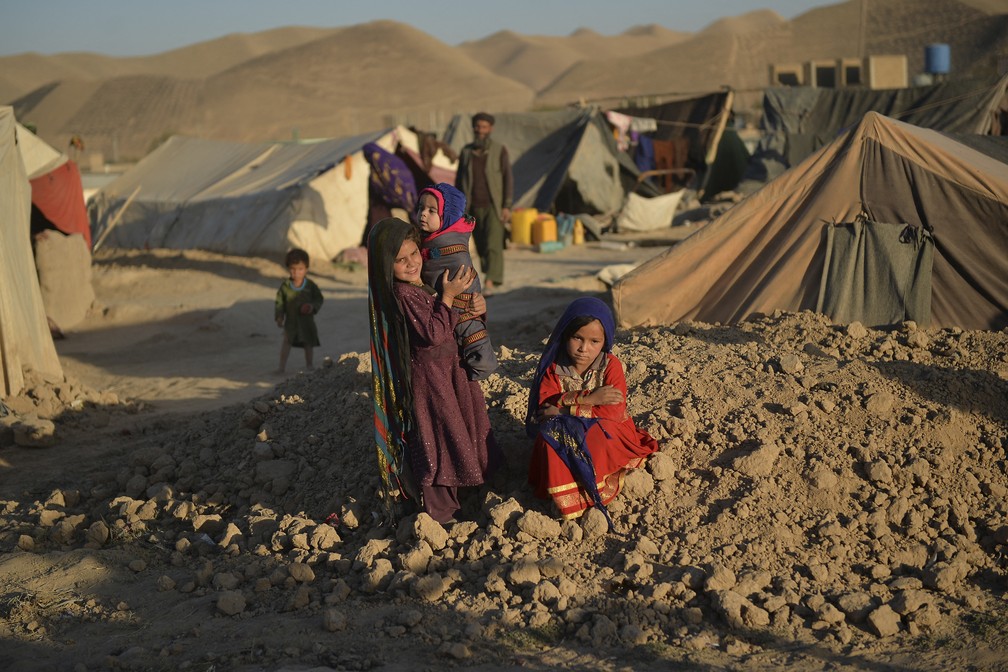 Asho (sentada), uma garotinha que ficou noiva de um homem de 23 anos por causa de dívidas da família, é fotografada em 14 de outubro de 2021 no campo de pessoas deslocadas de Shamal Darya, em Qala-i-Naw, capital da província de Badghis. O casamento infantil é praticado há séculos no Afeganistão, mas a guerra, a seca e a pobreza levaram muitas famílias a vender suas filhas cada vez mais cedo. — Foto: Hoshang Hashimi/AFP