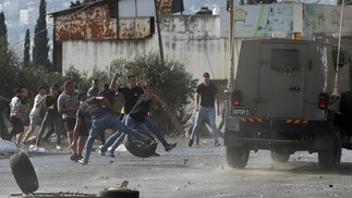Jovens palestinos jogam pedras em veículos do exército durante uma operação militar do exército israelense perto da cidade de Nablus, na Cisjordânia q — Foto: JAAFAR ASHTIYEH / AFP