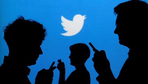 Pessoas usam celulares diante de logo do Twitter (Foto: Kacper Pempel/Reuters)